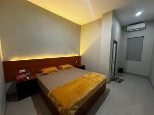 a bedroom with a bed with a yellow blanket at Grands Orchid Hotel in Lahat