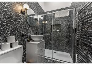 a black and white bathroom with a sink and a shower at Gorgeous Home VERY Close to the Fast Tube! in London