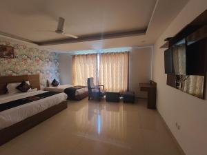 Hotel Ronit Royal - New Delhi Airport في نيودلهي: غرفة نوم بسريرين وتلفزيون بشاشة مسطحة