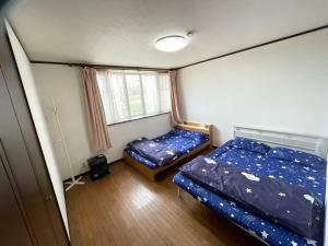 Habitación pequeña con 2 camas y ventana en 草津温泉、スキー場、湯畑、熱帯圏車で5分以内！最大27人宿泊可能 en Kusatsu