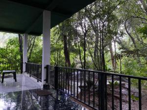 a porch of a house with a bench and trees at Green House Resort in Sigiriya