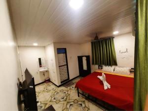 een kamer met een bed met een rode sprei en een kamer met: bij Ashirvad cottage in Alībāg