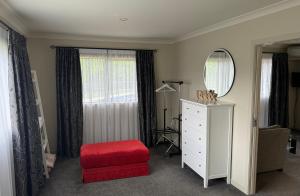 a bedroom with a red ottoman and a mirror at 200 on Lake View in Karapiro