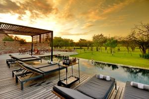 a deck with lounge chairs and a swimming pool at Ngala Lodge in Klipdrift