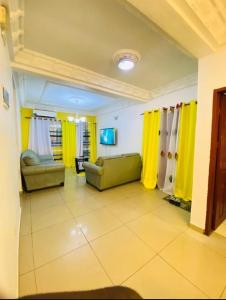 ein Wohnzimmer mit gelben Vorhängen und einer Couch in der Unterkunft Guesthouse & énergie in Douala