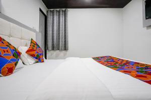 a white room with a bed with colorful pillows at FabHotel Park Residency in Mumbai