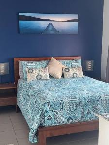 a bedroom with a bed with a blue wall at Spectacular Marina Views Apartment in Larrakeyah
