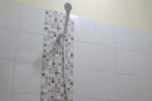 einem Duschkopf an der Seite einer gefliesten Wand in der Unterkunft Puri Karimunjawa RedPartner in Karimunjawa