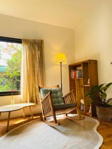 uma sala de estar com uma cadeira, uma mesa e uma janela em Elephant's House - Đường Lâm Homestay em Hanói