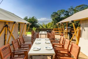 una fila de mesas y sillas en un patio en 山上種樹 l 苗栗豪華懶人露營Glamping l 柴燒泡湯 l 可包區森林系狩獵帳 l 牛樟森林休閒農場 en Miaoli