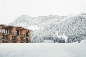 a building with snow on the ground in front of a mountain at Hotel Nesslerhof in Grossarl