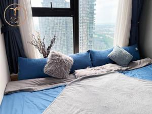 Cama azul con almohadas frente a una ventana en Armin Homes 2 Bedroom apartment at Ecopark, en Kim Quan