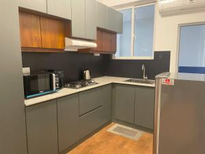 eine Küche mit grauen Schränken, einer Spüle und einer Mikrowelle in der Unterkunft Rush Resident Mount Lavinia in Mount Lavinia