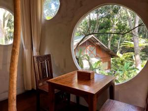 a table and a chair in a room with two large windows at Imah Seniman in Lembang