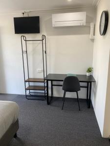 een kamer met een bureau, een stoel en een ventilator bij The Seaview Tavern Motel in Woolgoolga