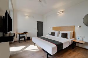 1 dormitorio con 1 cama blanca grande y TV en Super Townhouse 124 Srm Kuppakonam Pudur en Coimbatore