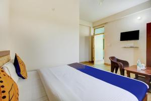 Schlafzimmer mit einem Bett, einem Schreibtisch und einem TV in der Unterkunft SPOT ON Chandra's Residence in Dehradun