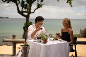 a man and woman sitting at a table with wine glasses at Tamarina Golf & Spa Boutique Hotel in Flic-en-Flac