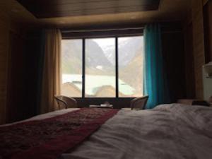 a bedroom with a bed and a large window at Hotel Badrinath Anant Badrinath in Badrīnāth