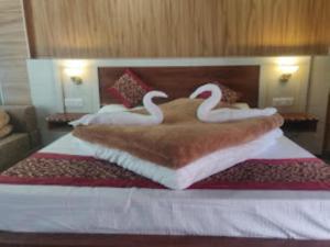 two swans on a bed in a hotel room at Hotel Badrinath Anant Badrinath in Badrīnāth