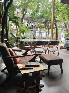 um pátio com cadeiras e mesas e uma mesa com controlos remotos em Q' Homestay Garden Villa em Hue