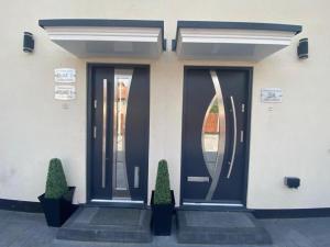 a pair of doors on a building with two plants at THE ROYAL BOUTIQUE OXFORD LODGE BY LONDON HEATHROW UK, PRIVATE APARTMENT OFFER's FREE PARKING, WIFI , KITCHEN & LAUNDRY SERVICES, SLEEP 8 in Hayes