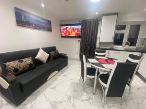 a living room with a couch and a table with chairs at THE ROYAL BOUTIQUE OXFORD LODGE by LONDON SLEEP 6 in Hayes