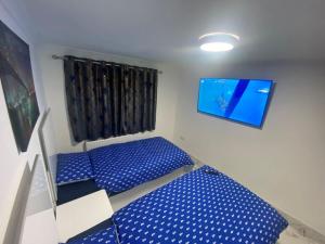 Habitación con 2 camas azules y TV de pantalla plana. en THE ROYAL BOUTIQUE OXFORD LODGE by LONDON SLEEP 8 en Hayes