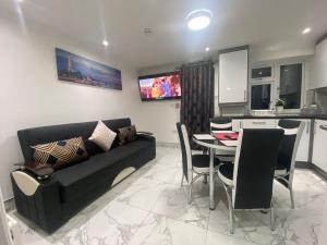 a living room with a black couch and a table at THE ROYAL BOUTIQUE OXFORD LODGE by LONDON SLEEP 8 in Hayes