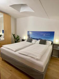 ein großes weißes Bett in einem Schlafzimmer mit einem blauen Plakat an der Wand in der Unterkunft Apartment Ladinger in Radstadt