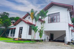 a white house with palm trees in front of it at Antique Tourist Lodge in Kandy