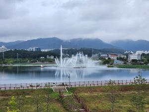 a fountain in the middle of a lake with a city at Gyeongsan Lake View - Mid Century and Workcation in Gyeongsan