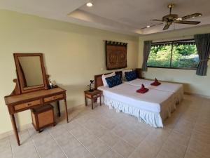a bedroom with a bed and a mirror and a table at Villa Oranje Chiang Mai in Chiang Mai