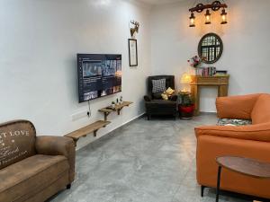 a living room with a couch and a tv at Jessie Home in Bukit Mertajam