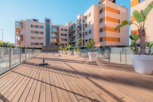 una terraza de madera con macetas y edificios en Apartamento LUZ DE MAR, en El Campello