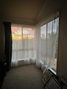 MoggillにあるBrisbane Zen spaceの白いカーテン付きの大きな窓が備わる客室です。