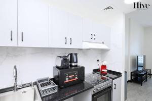 a kitchen with white cabinets and a black microwave at Cosy Studio in Skycourts Tower in Dubai