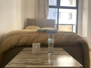 Heart of Abu Dhabi - Superb Room في أبوظبي: وجود زجاجة مياه على طاولة بجوار سرير