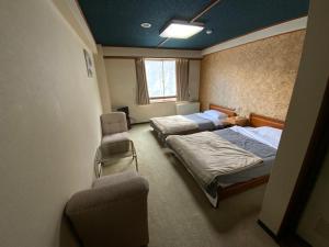 a bedroom with two beds and a chair and a window at ロッヂ　スガノ in Zaō Onsen