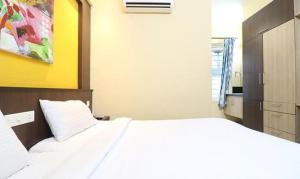 um quarto com uma cama branca e uma parede amarela em FabHotel Elite Inn em Trivandrum