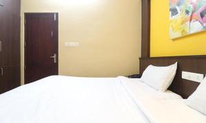 um quarto com uma cama grande e lençóis brancos em FabHotel Elite Inn em Trivandrum