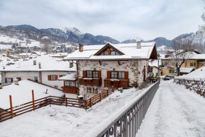 una casa está cubierta de nieve en un pueblo en B.& B. Corradini en Castello di Fiemme