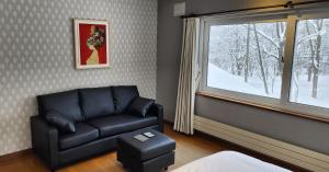 a living room with a couch and a window at El Cosmo Lodge, Niseko in Niseko
