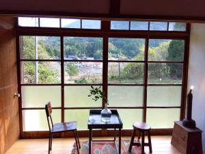 唐津朝食付唐津里山の宿&ヨガ兎と亀②的一间设有一张桌子和椅子的客房,位于大窗户前