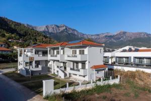 a white apartment building with mountains in the background at Elisavet Nuevo Studios & Suites in Skala Potamias