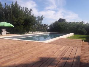 a swimming pool with a wooden deck and an umbrella at Le Dojo du Plessis in Mareuil