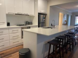 a kitchen with a large white island with bar stools at Stylish 4 Bedroom Urban Retreat in Wagga Wagga +5 photos