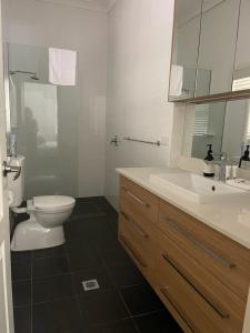 ein weißes Bad mit einem WC und einem Waschbecken in der Unterkunft Stylish 4 Bedroom Urban Retreat in Wagga Wagga