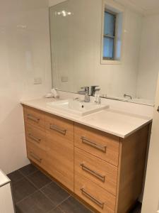 a bathroom with a sink and a mirror at Stylish 4 Bedroom Urban Retreat in Wagga Wagga