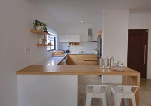 una cucina con bancone in legno e 2 sgabelli bianchi di Modern Villa in Grand Bay - Short Walk to Beach a Grand Baie